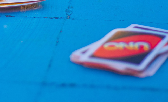 Unscharfer Uno-Kartenstapel auf leuchtend blauer Oberfläche.